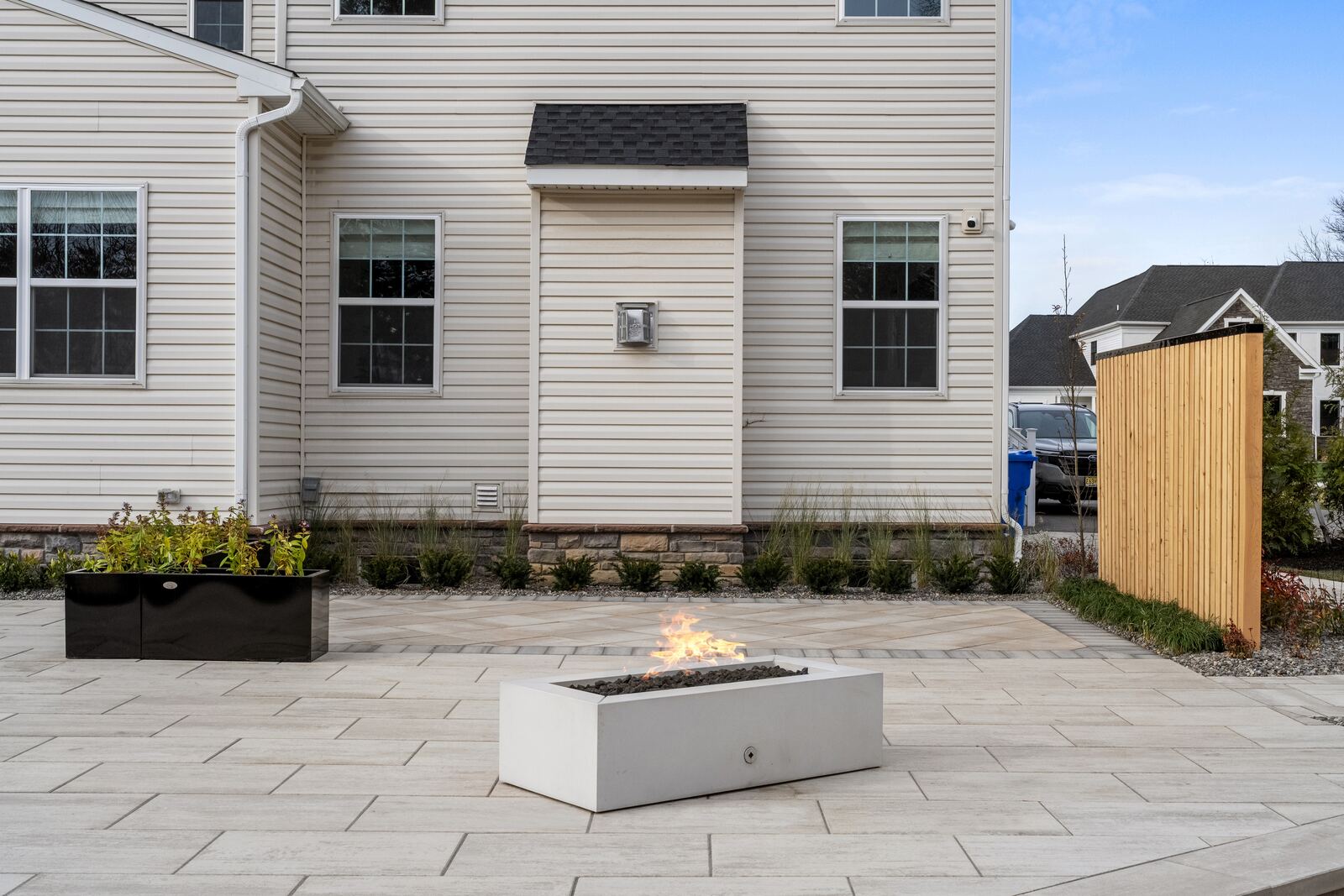 Concrete fire table on a porcelain patio beside a cedar privacy screen